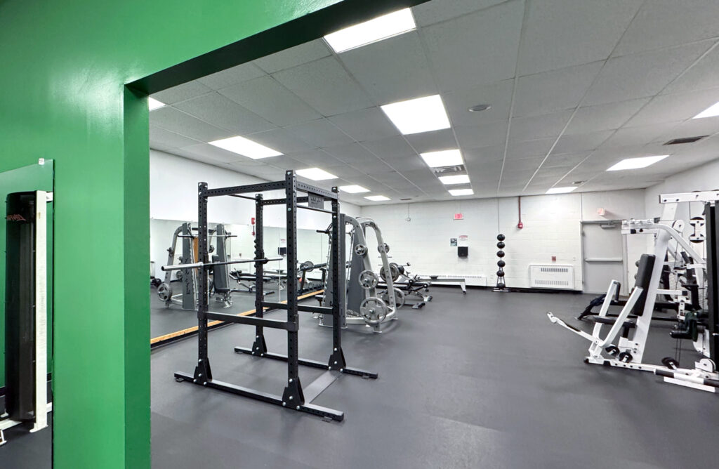 Photo of the inside of the Black Bear Fitness Center, shoting a squat rack and wieght benches
