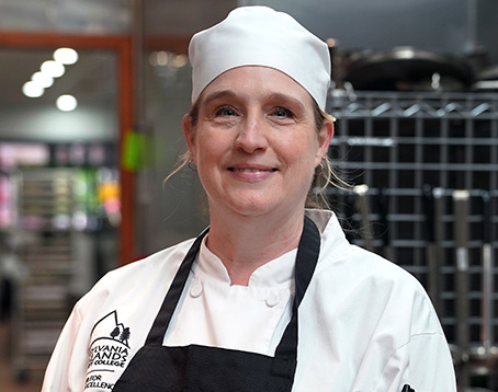 Posed photo of Kat Walker in her chef gear, in the Culinary Center.