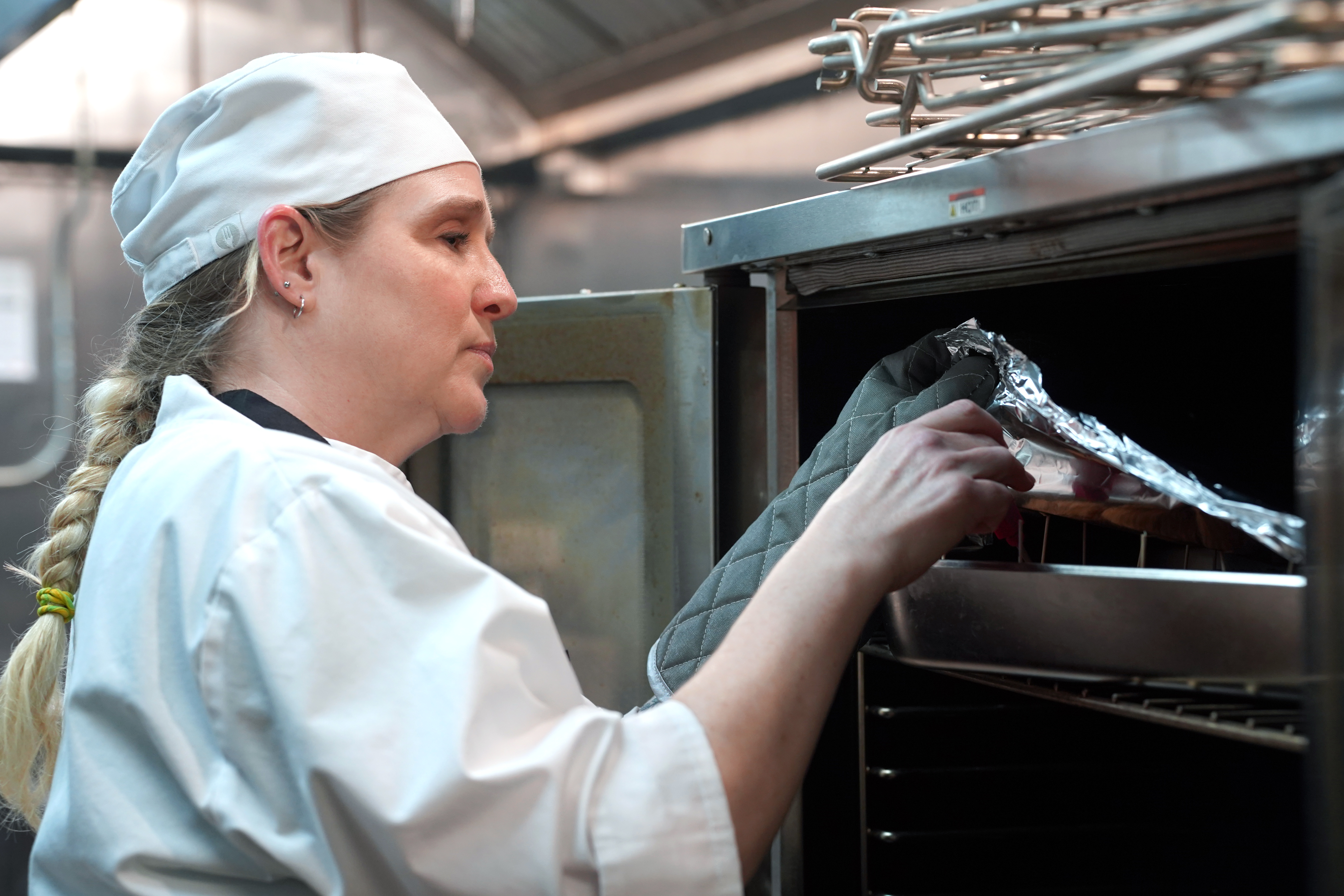 Kat Walker, chef student, placing food in the oven.