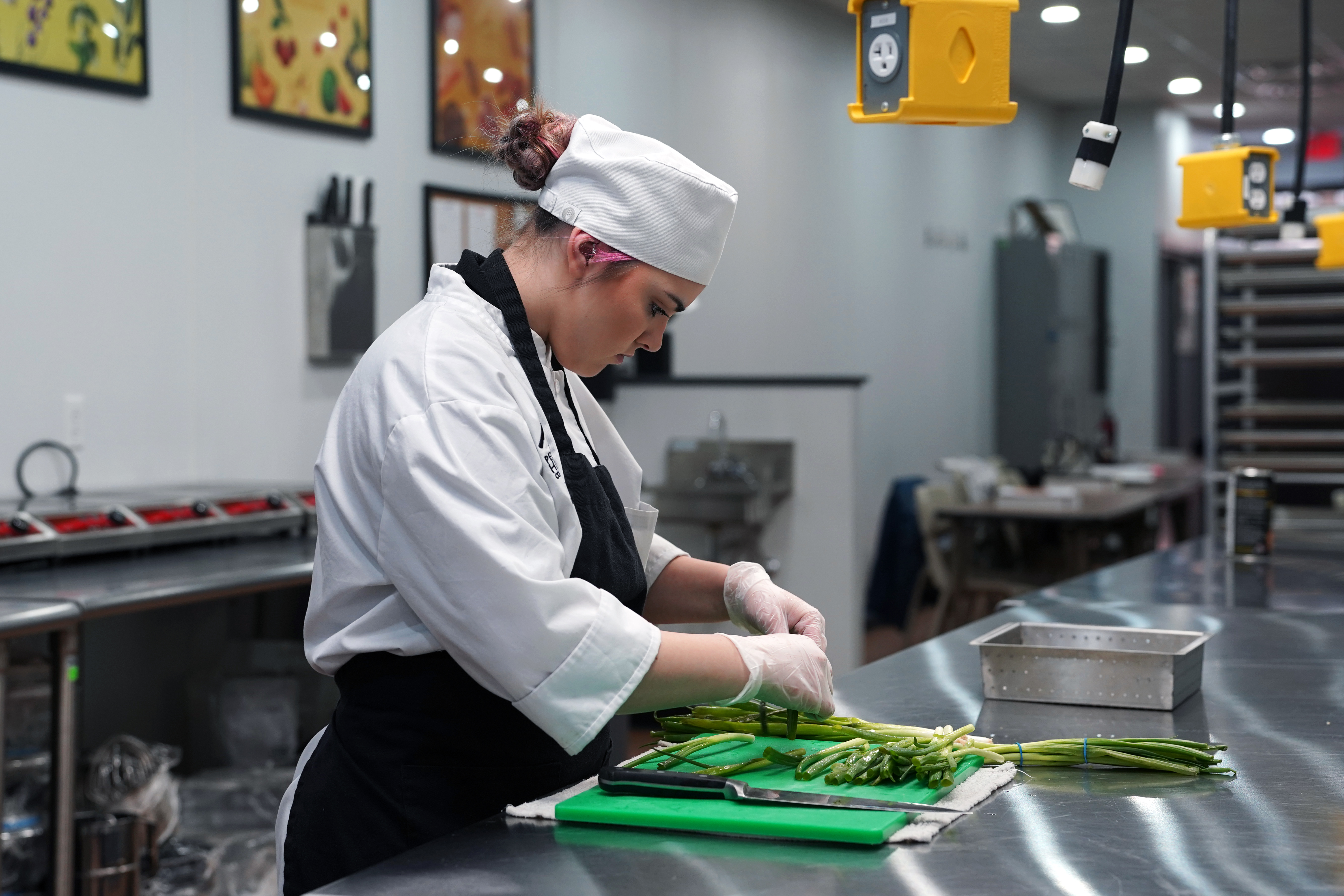 Trininty Hyatt, chef student, working with asparagus in the culinary kitchen.